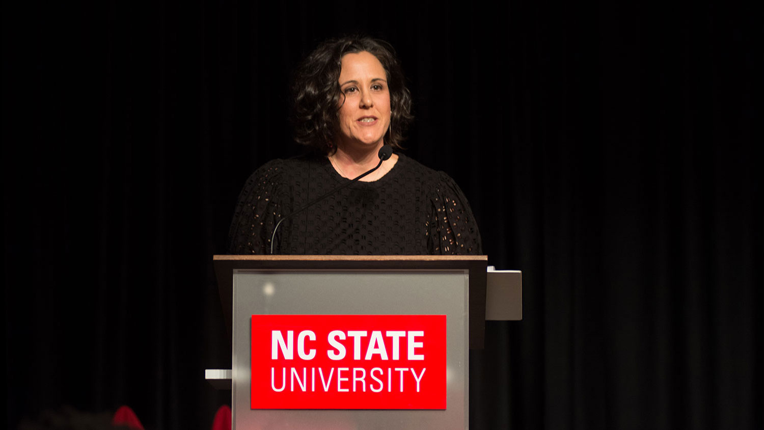 Lisa LaBarbera-Mascote standing behind an NC State podium